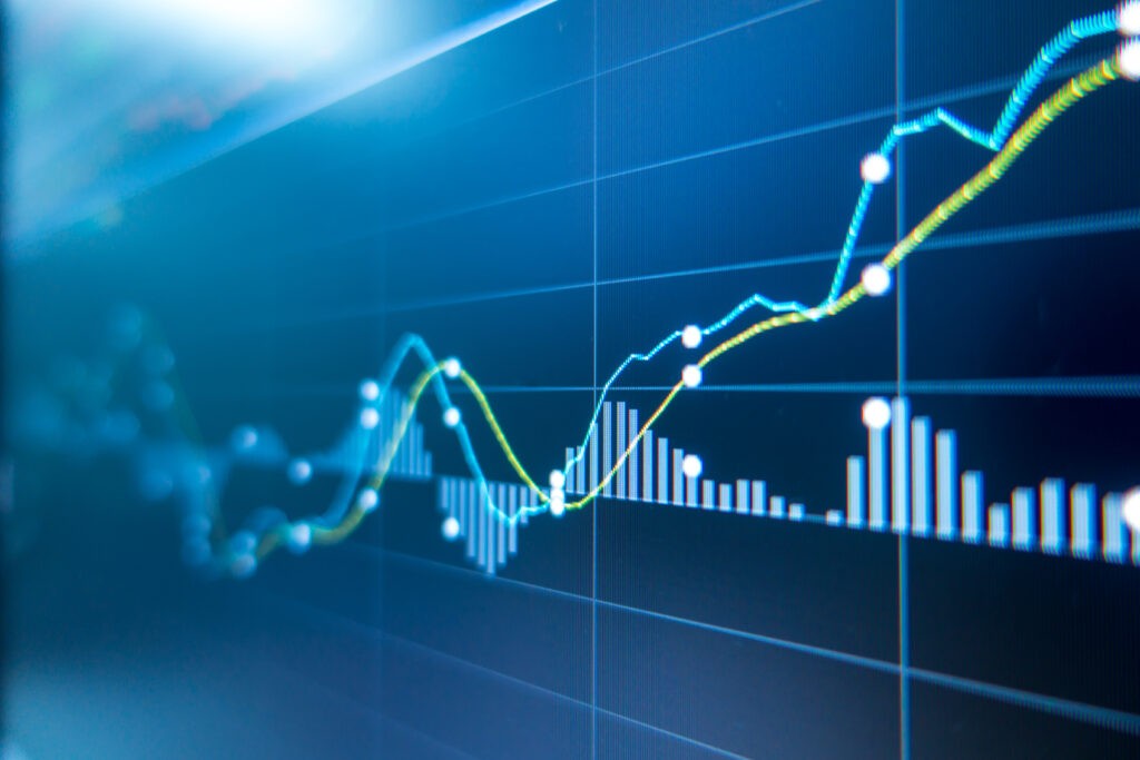 A close-up of a digital screen displaying fluctuating line graphs and bar charts, indicating data analysis or financial market trends. 