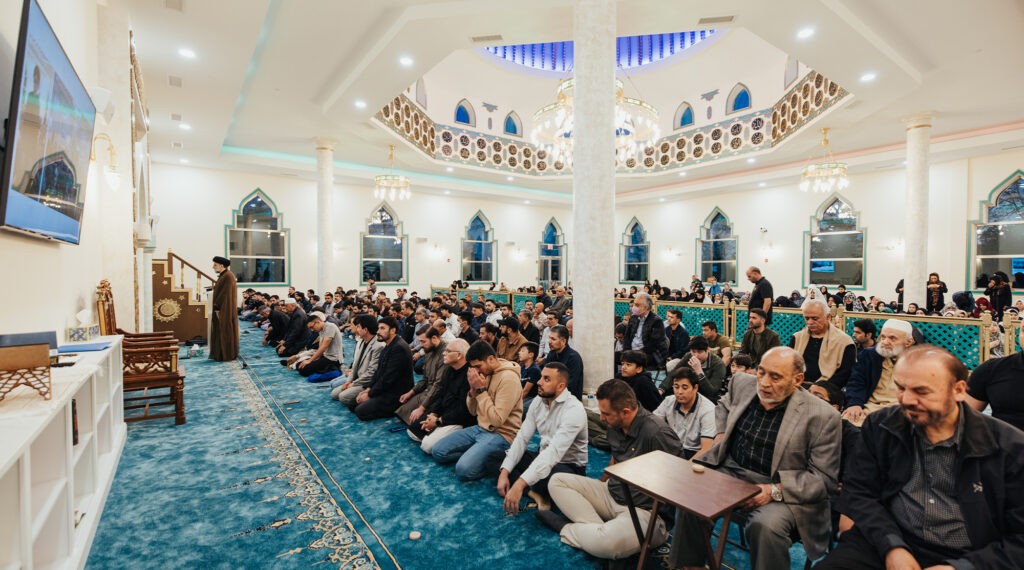 Congregants seated in a mosque during prayer, attentively listening to the call to prayer.