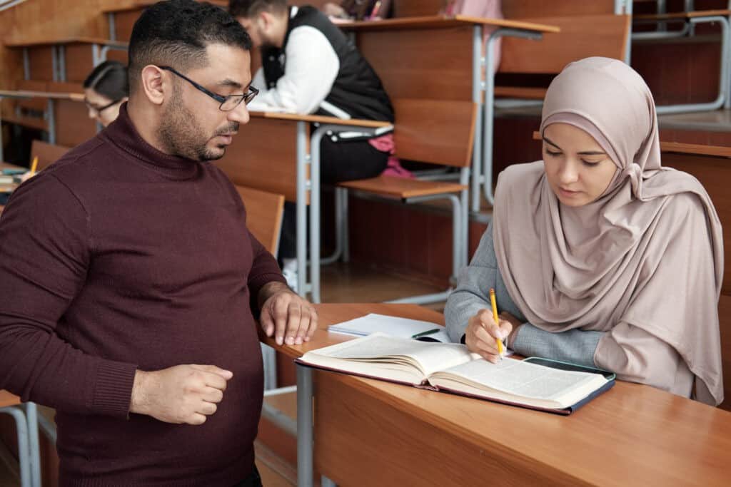 Confident teacher consulting one of the female students