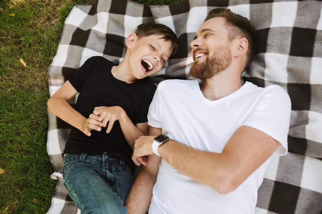 Image of happy young father have fun with his little son outdoors in park nature.
