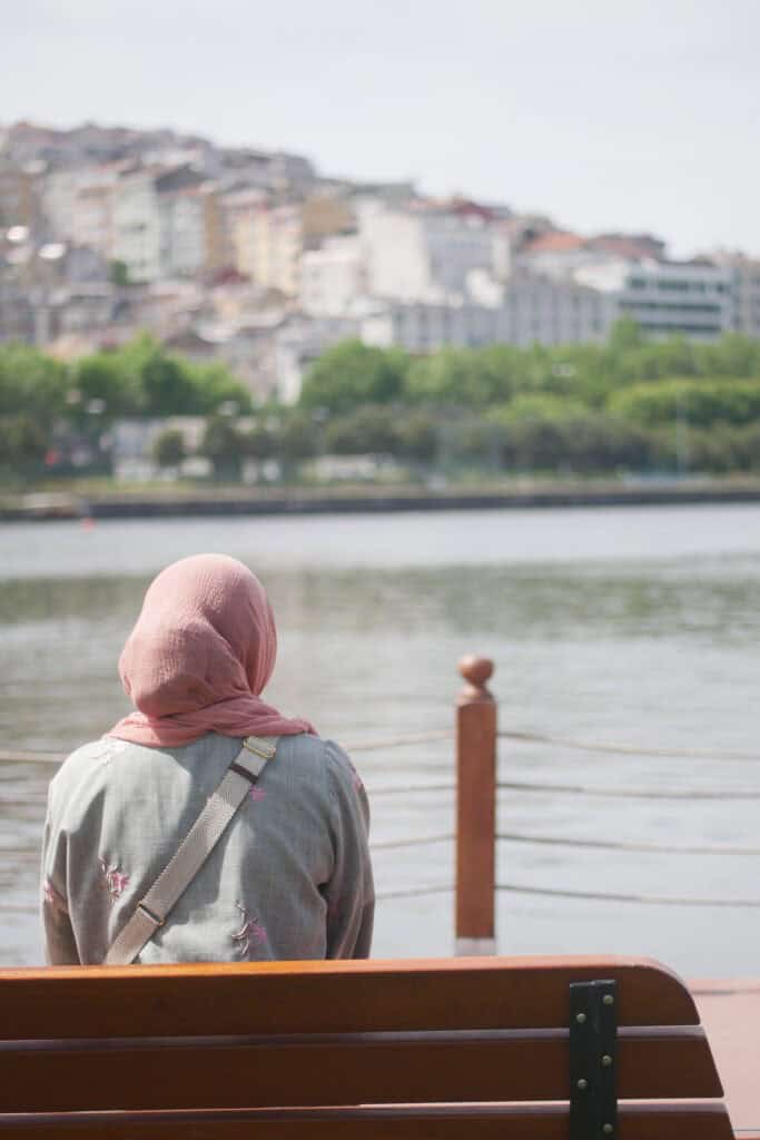 girl sitting at bench near water